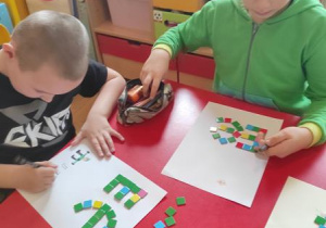 Dzieci wyklejają literę e.